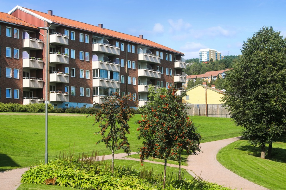 Våningshus med balkonger och en grön äng framför