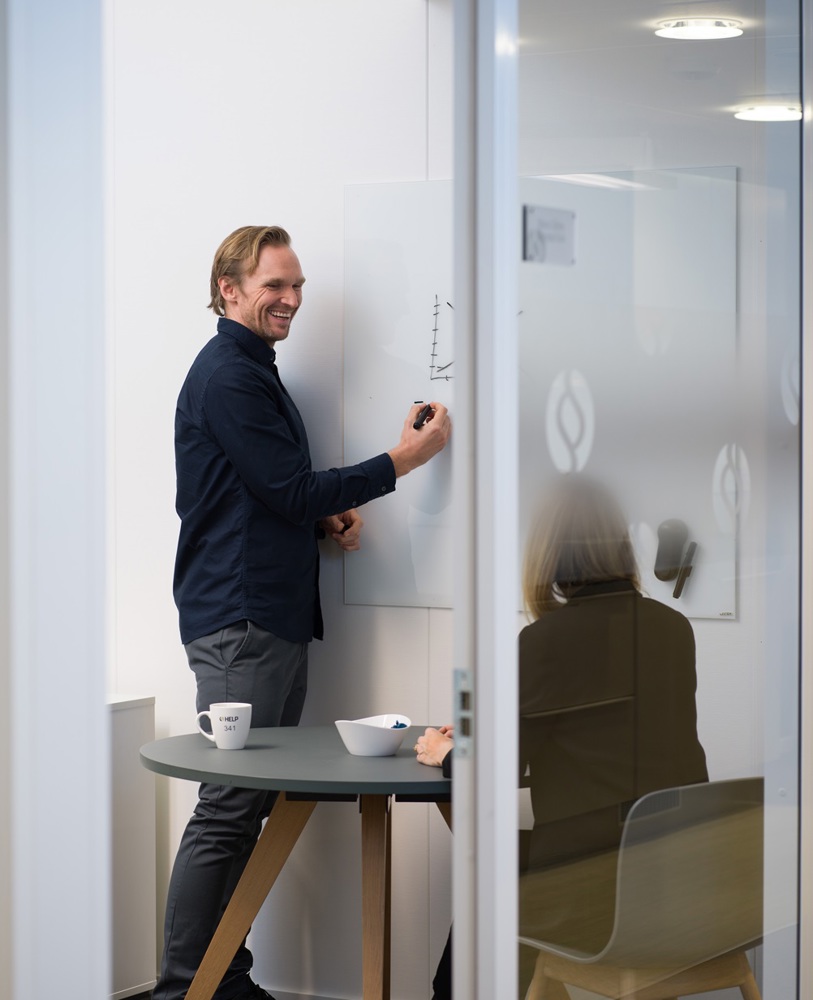 Man som skriver på en whiteboard och skrattar